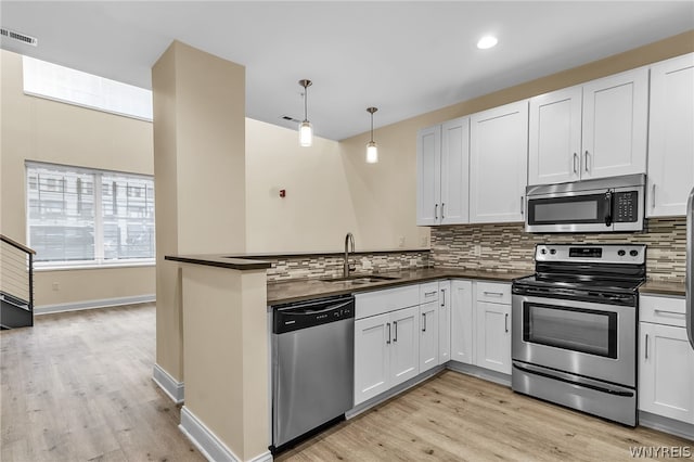 kitchen with light hardwood / wood-style flooring, tasteful backsplash, kitchen peninsula, stainless steel appliances, and sink