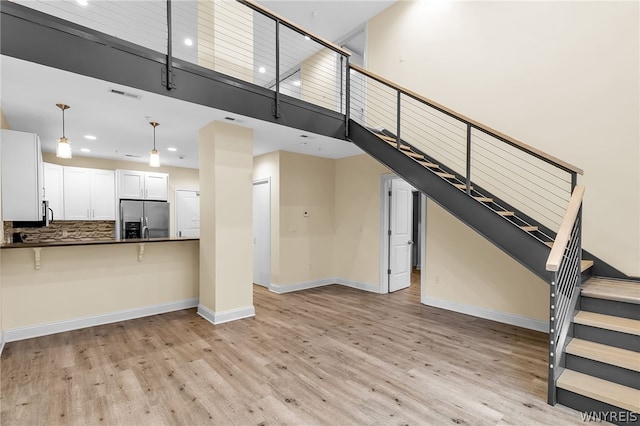 unfurnished living room featuring light wood-type flooring and a high ceiling