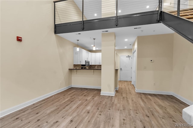 unfurnished living room featuring light wood-type flooring and a towering ceiling