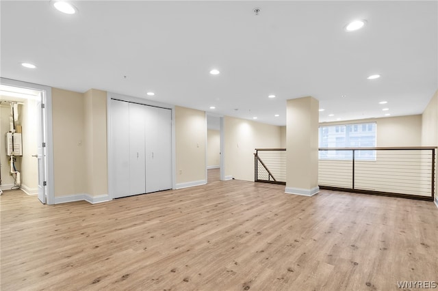 unfurnished living room featuring light hardwood / wood-style flooring and water heater