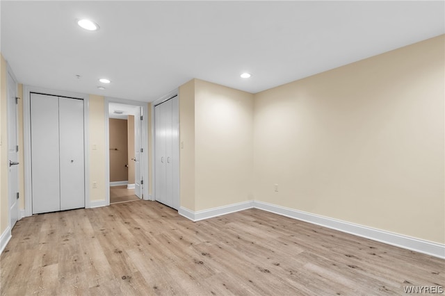 unfurnished bedroom with two closets and light wood-type flooring