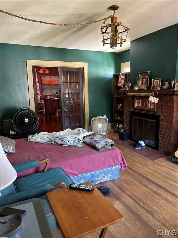 bedroom with an inviting chandelier, hardwood / wood-style flooring, and a fireplace