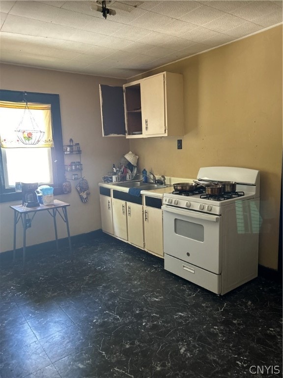 kitchen featuring white cabinets, sink, and white gas range