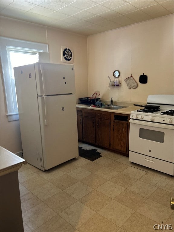 kitchen with dark brown cabinetry, white appliances, and sink