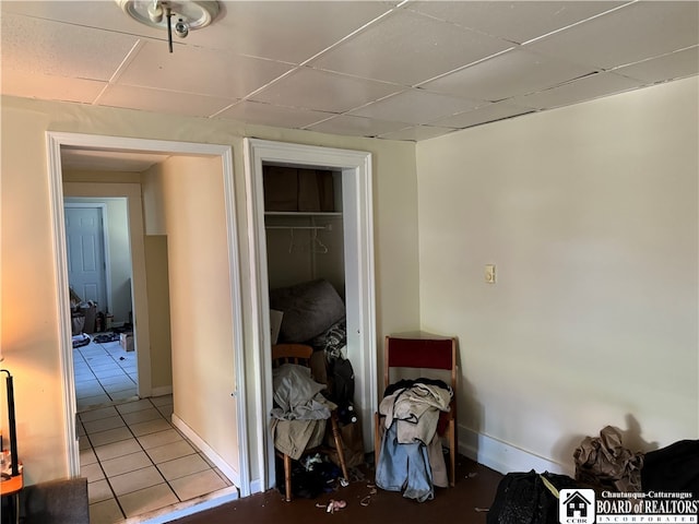 bedroom with a drop ceiling, a closet, and light tile patterned floors