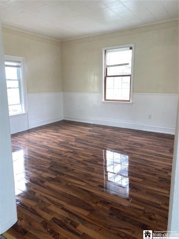 empty room featuring ornamental molding and dark wood-type flooring