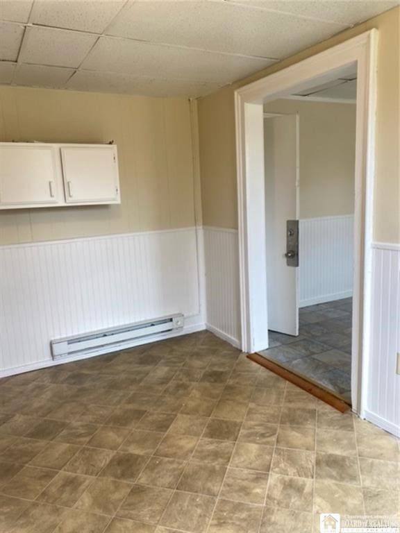 unfurnished room with a paneled ceiling and a baseboard heating unit