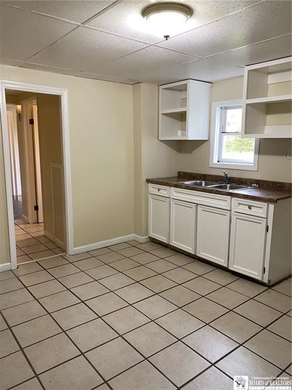 51 Fairmount Ave, Jamestown, NY 14701 - kitchen with open shelves, a sink, dark countertops, white cabinetry, and light tile patterned flooring