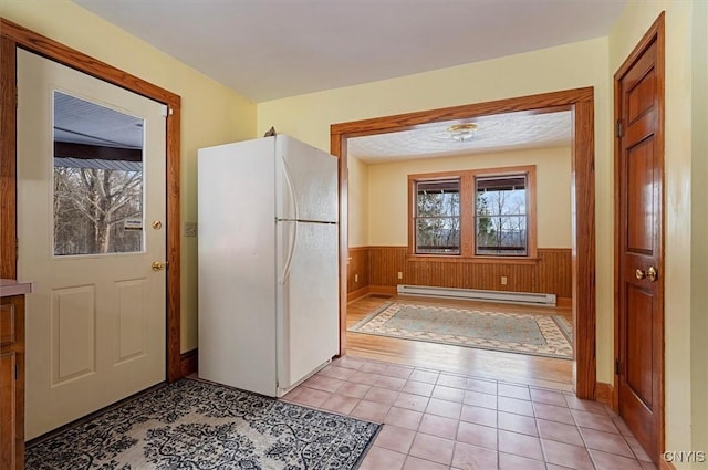 interior space featuring wooden walls, light tile patterned floors, and a baseboard heating unit