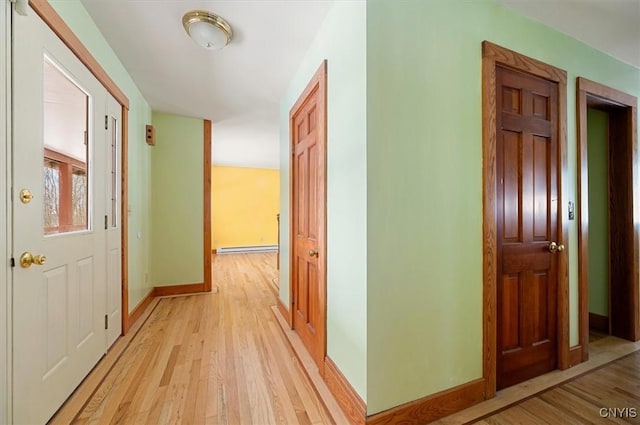 corridor with a baseboard radiator and light hardwood / wood-style floors