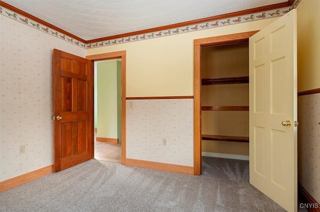 unfurnished bedroom featuring ornamental molding, carpet flooring, and a closet