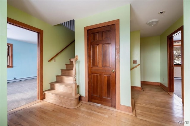 stairs featuring hardwood / wood-style floors and baseboard heating