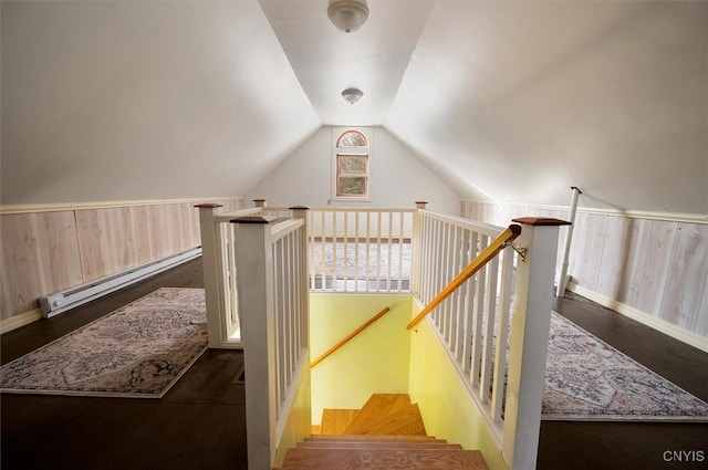 staircase with vaulted ceiling, wooden walls, and baseboard heating