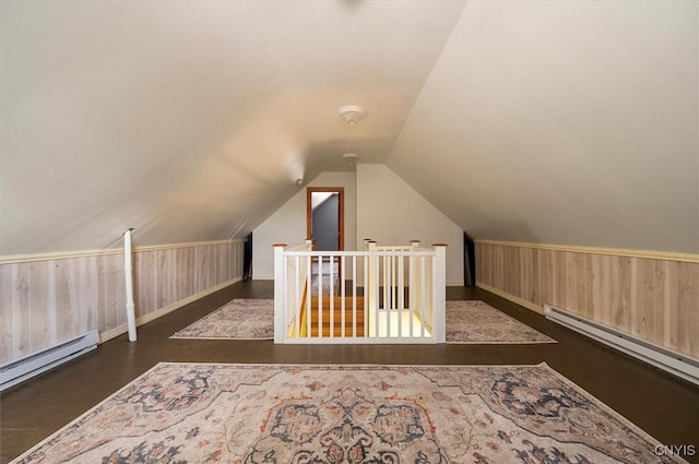 additional living space featuring a baseboard radiator, lofted ceiling, and wood walls