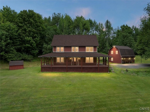 back house at dusk with a porch, a yard, and a shed