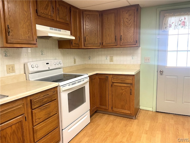 kitchen with light wood-type flooring, white electric stove, and backsplash