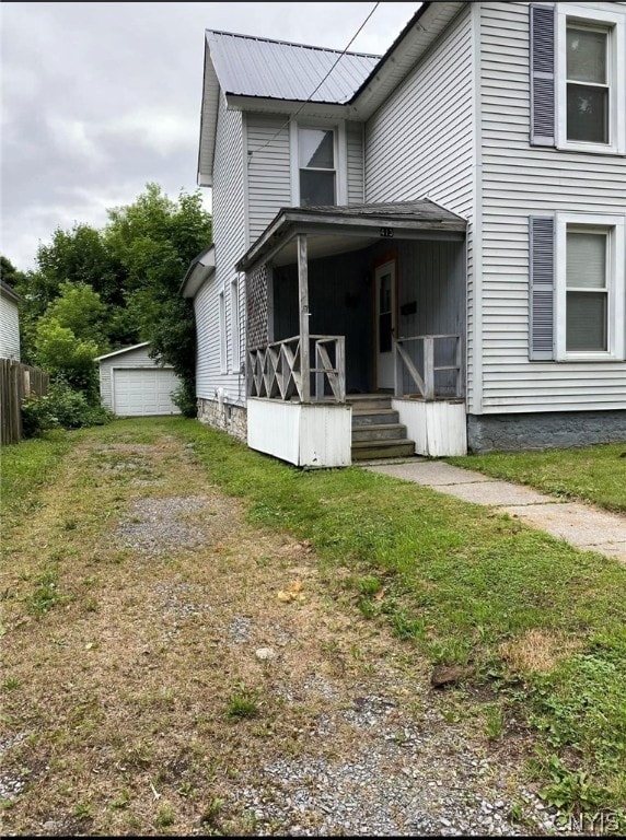 view of front facade with an outbuilding, a porch, a garage, and a front lawn