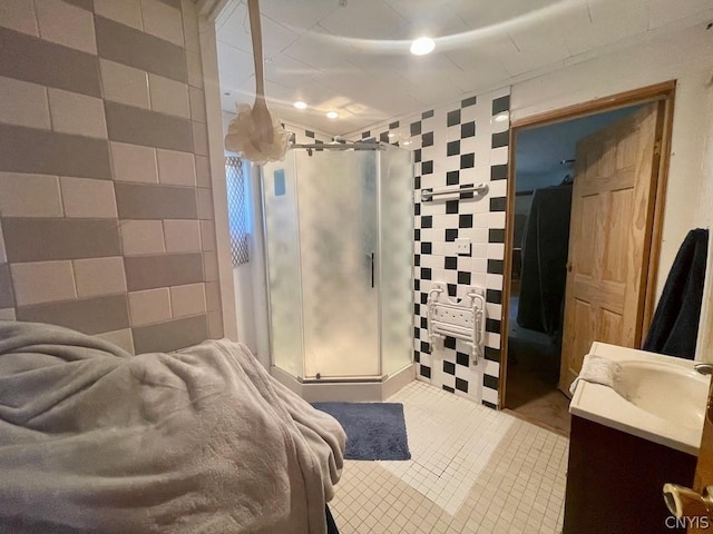 bathroom featuring tile patterned flooring, a shower stall, tile walls, and vanity