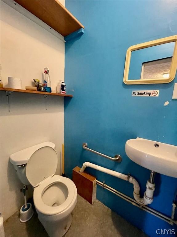 bathroom with toilet and concrete flooring