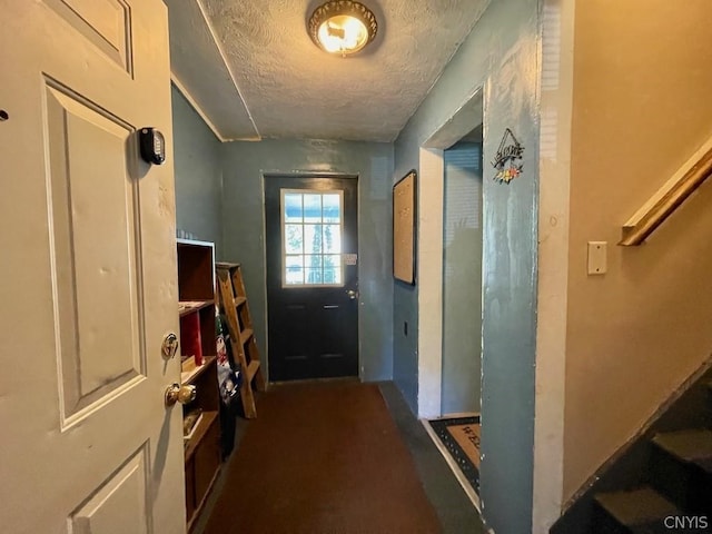 doorway to outside with a textured ceiling