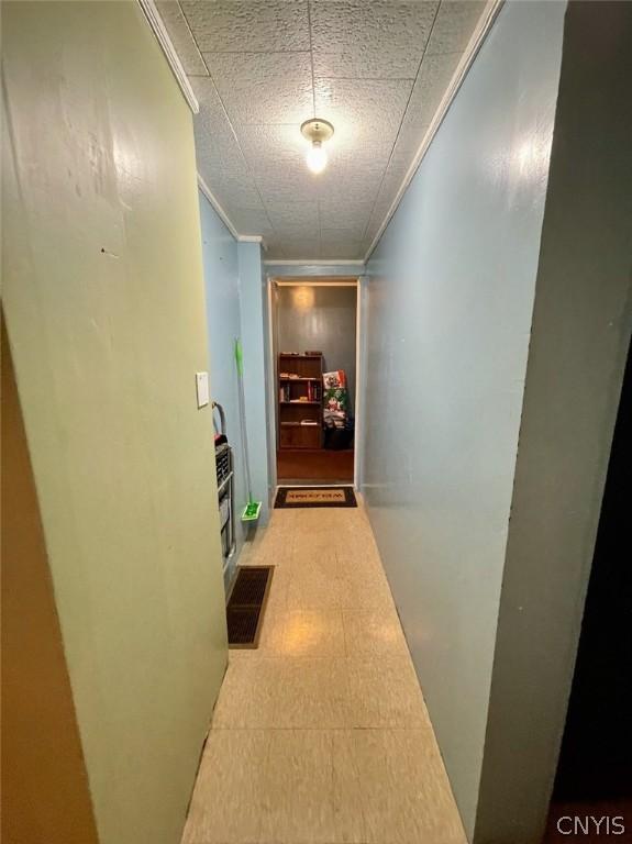 hall featuring light floors, visible vents, and crown molding