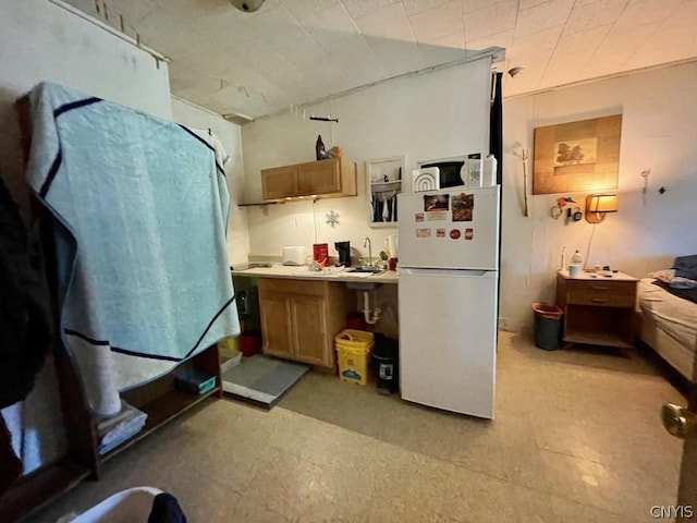 kitchen with brown cabinets, white appliances, light countertops, and a sink