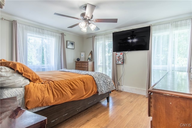 bedroom featuring crown molding, light hardwood / wood-style floors, multiple windows, and ceiling fan