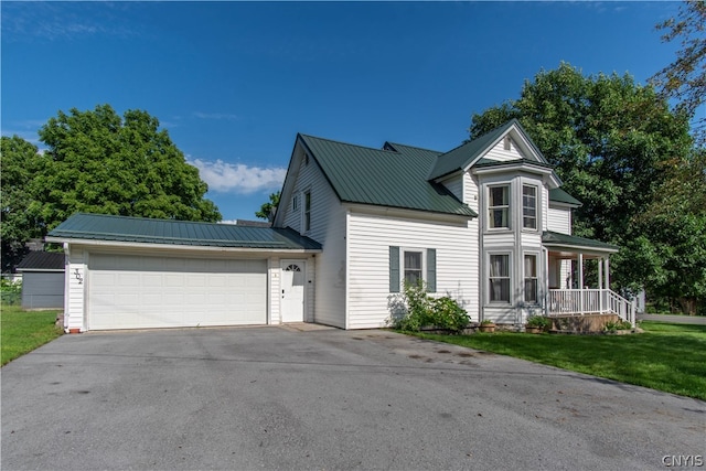 view of front of property featuring a porch, a garage, and a front lawn