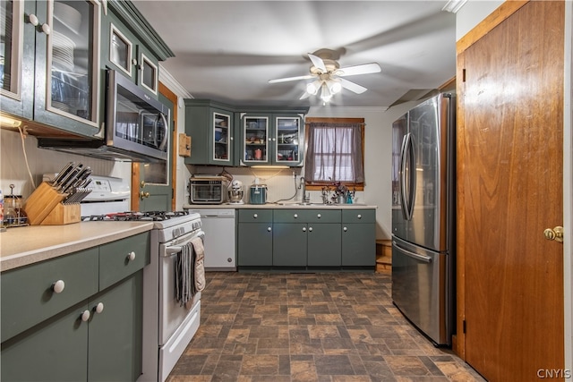 kitchen featuring appliances with stainless steel finishes, sink, dark tile patterned flooring, crown molding, and ceiling fan