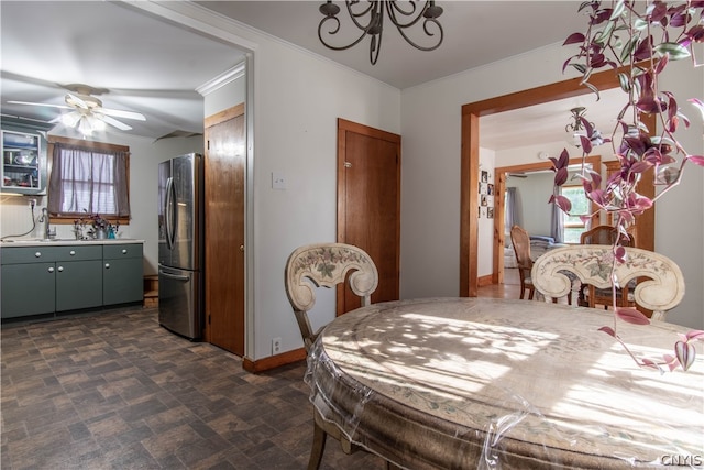 dining space with sink, a wealth of natural light, ceiling fan with notable chandelier, and crown molding