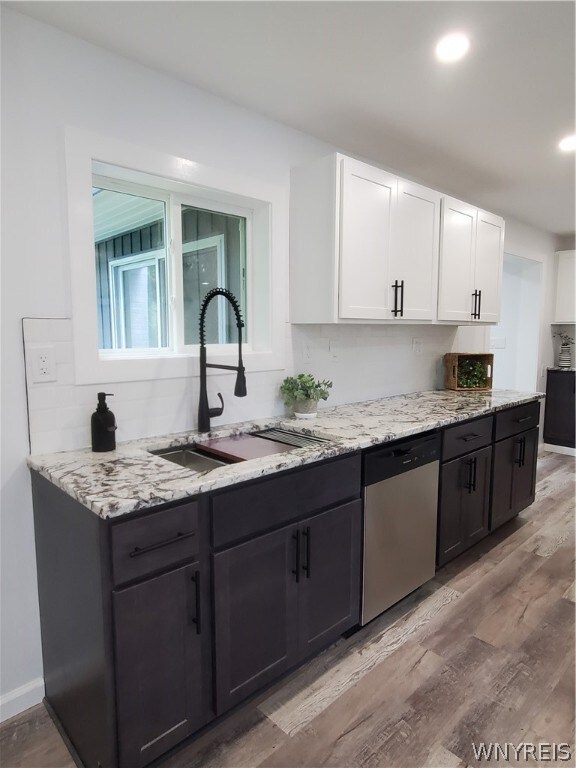 kitchen featuring sink, dishwasher, white cabinets, and light wood-type flooring