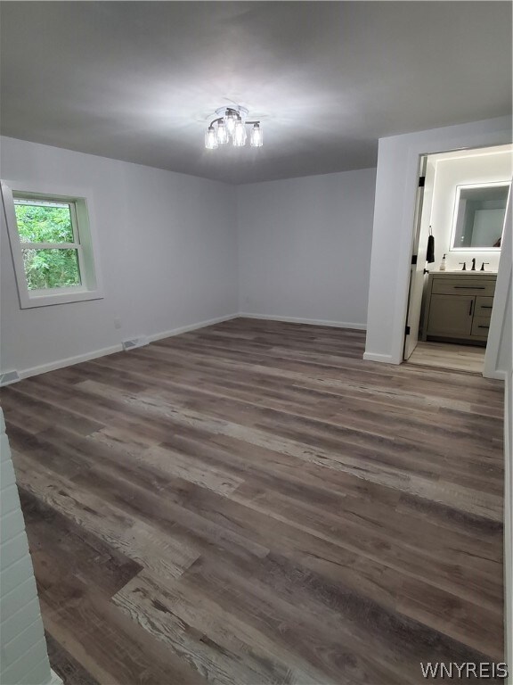 unfurnished bedroom featuring connected bathroom and hardwood / wood-style floors