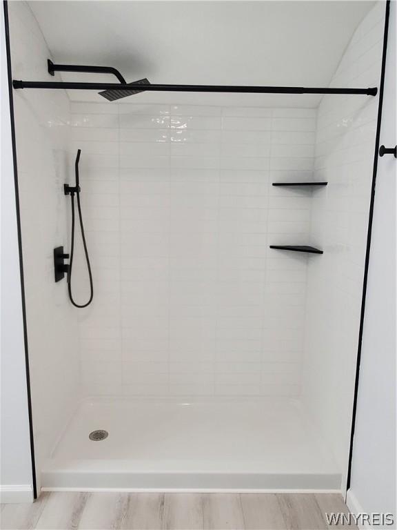 bathroom with tiled shower and hardwood / wood-style flooring