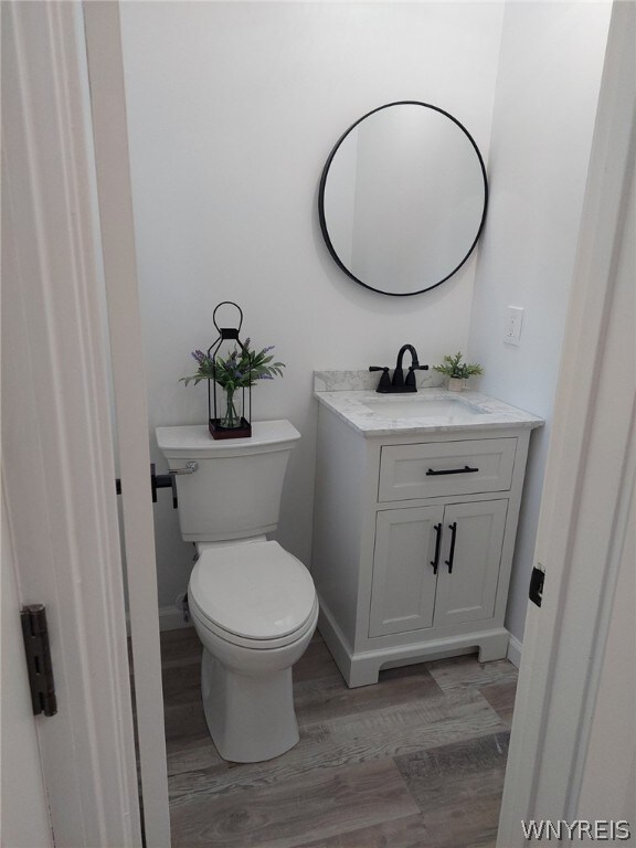 bathroom with vanity, toilet, and hardwood / wood-style floors