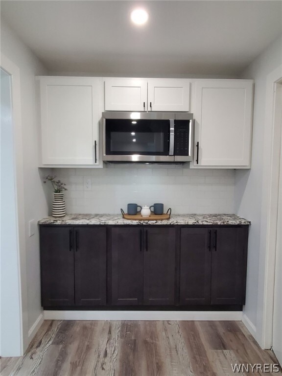 kitchen with white cabinets, light stone counters, and light wood-type flooring