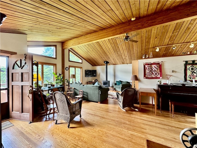 living room featuring lofted ceiling with beams, a wood stove, light hardwood / wood-style flooring, and wooden ceiling