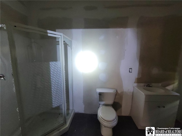 bathroom featuring a shower with shower door, toilet, and vanity