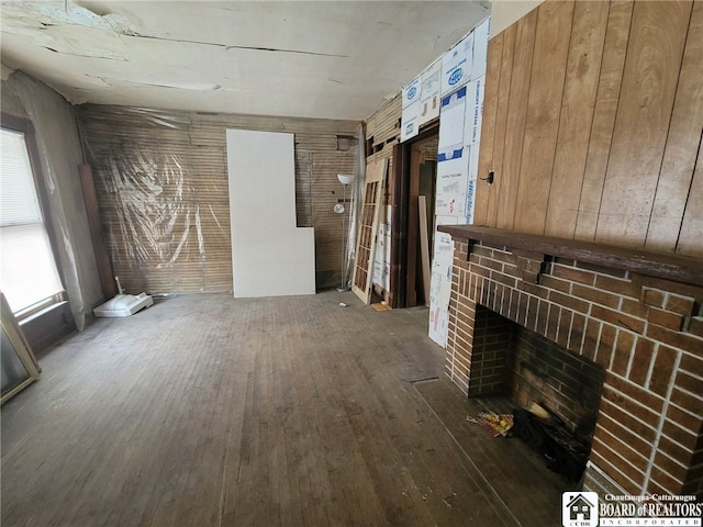 unfurnished living room featuring a brick fireplace and dark wood-type flooring