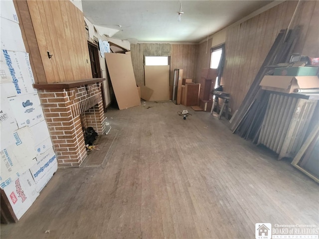 unfurnished living room featuring wood walls, a brick fireplace, and hardwood / wood-style floors