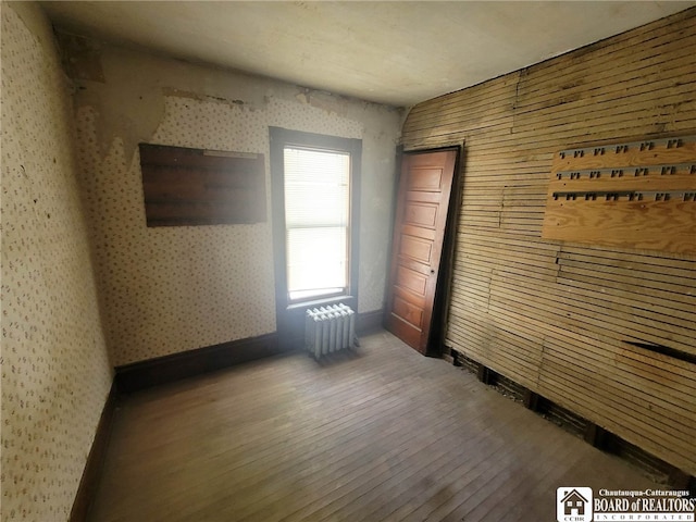 unfurnished room featuring radiator heating unit and hardwood / wood-style floors