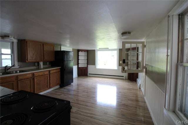 kitchen featuring sink, light hardwood / wood-style flooring, a baseboard heating unit, and black appliances