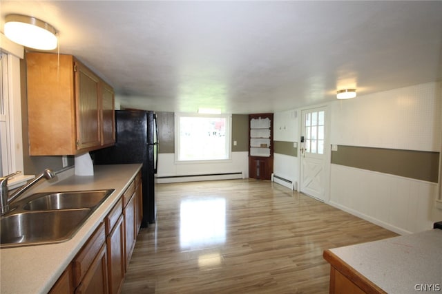 kitchen with baseboard heating, sink, and light hardwood / wood-style flooring