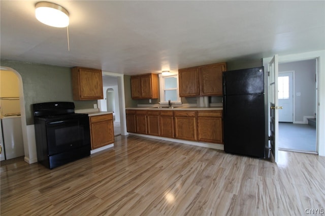 kitchen with sink, light hardwood / wood-style flooring, and black appliances