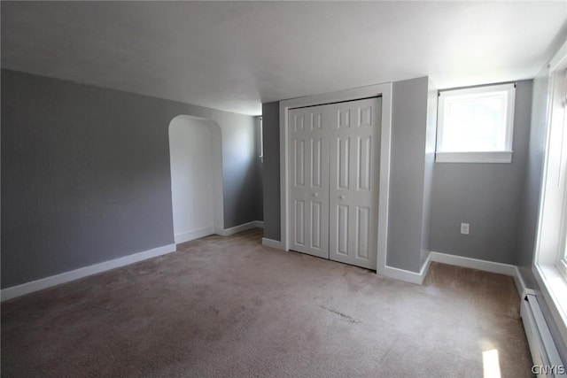 850 County Route 37, Hastings, NY 13036 - unfurnished bedroom with carpet flooring, arched walkways, a baseboard heating unit, baseboards, and a closet