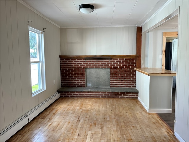 unfurnished living room with a baseboard heating unit, light hardwood / wood-style flooring, ornamental molding, and plenty of natural light