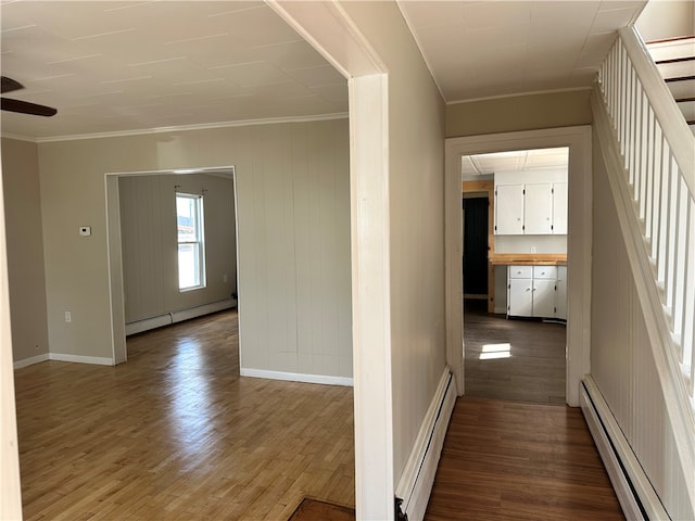 hallway with a baseboard radiator, hardwood / wood-style flooring, and ornamental molding