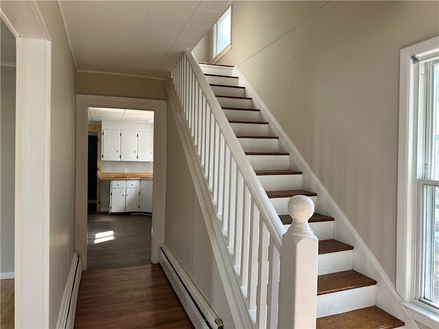 staircase with baseboard heating and dark hardwood / wood-style flooring