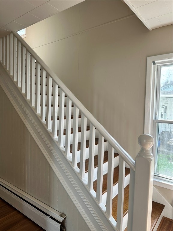 staircase featuring wood-type flooring and a baseboard heating unit