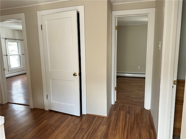 hallway with dark hardwood / wood-style floors, baseboard heating, and ornamental molding