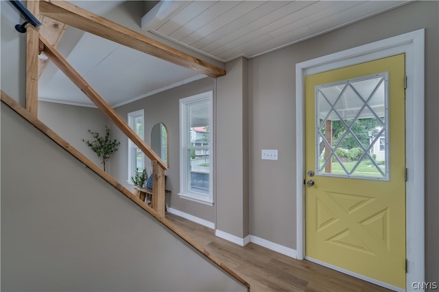 foyer entrance featuring beamed ceiling, a wealth of natural light, crown molding, and hardwood / wood-style floors